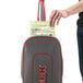 A person putting a bag with a label on it in a grey and red Oreck vacuum cleaner.