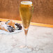 A Spiegelau Willsberger flute filled with champagne on a table with a pastry.