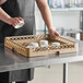 A woman holding a white bowl in a Vollrath dish rack on a counter.