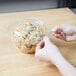 A hand holding a Polar Pak plastic container filled with pasta.