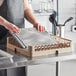 A woman holding a Vollrath metal rack on a counter.