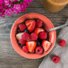 A Tuxton Concentrix Cinnebar china bowl filled with fruit.