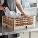 A woman using a Vollrath beige dish rack to hold white plates.