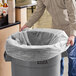 A man holding a Lavex plastic bag over a trash can.