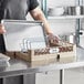 A man in an apron using a Vollrath Traex sheet pan rack on a plastic tray.