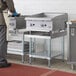 A man standing in front of a Regency stainless steel equipment stand with a galvanized undershelf.