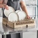 A woman holding plates in a Vollrath beige dish rack.