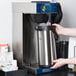 A person using a Bloomfield commercial pourover coffee maker on a counter.