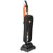 A black and orange Hoover Task Vac commercial bagged vacuum cleaner with a handle.