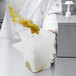 A hand pouring liquid into a Carlisle container on a counter.