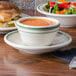 A bowl of soup and a sandwich on plates.