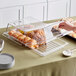 A hand holding a Cambro display tray of pastries on a counter.