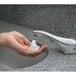 A person using a Bobrick deck mounted automatic liquid soap dispenser to wash their hands.