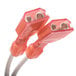 A close-up of a red electrical connector with two orange cables and white connectors.