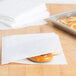 A bagel in a white paper cone bag.