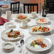 A table with Homer Laughlin ivory oval china platters of food and a wine glass.