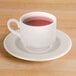 A white Homer Laughlin Seville saucer with a white cup of red tea.
