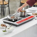 A person using an Avantco double countertop induction range to cook meat in a pan.