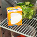 A box of Arm & Hammer Fridge-N-Freezer Baking Soda on a shelf in a refrigerator with broccoli.