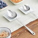 An American Metalcraft stainless steel hammered spoon on a table with bowls of oatmeal and blueberries.