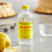 A bottle of Shank's Pure Lemon Extract on a table next to a lemon.