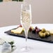 A Stolzle Exquisit flute glass filled with champagne on a table in a winery cellar.