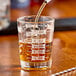 A Libbey clear measuring glass with brown liquid in it.