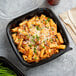 A black plastic hinged take-out container with pasta and cheese on top.