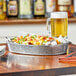 A Tablecraft oval galvanized steel platter with nachos on a table.