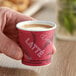 A hand holding a red Solo Bistro paper hot cup of coffee with a lid.