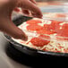 A person holding a clear plastic container with a Solut black lid containing pizza.