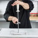 A chef using a Dexter-Russell oval diamond knife sharpening steel with a white handle on a knife.