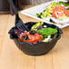 A bowl of salad with a black fork.