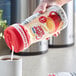 A hand pouring Nestle Coffee-Mate from a plastic bottle into a cup of coffee.