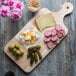 A cutting board with cheese and salami on it.