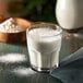 A glass of milk with a spoon next to it.