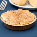 A small pie in a Solut Kraft Paper Baking Cup with a fork on a table.