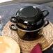 A black Hendi enameled steel mussel pot with a lid on a table.