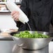 A person using a FIFO Innovations squeeze bottle to pour white dressing onto a bowl of salad.