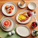 A table with Acopa brown speckle saucers holding plates and bowls of food with a cup of coffee on a saucer.