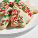 A plate of Christmas-themed sugar cookies decorated with white icing and red, green, and white sprinkles.