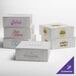A stack of white customizable cake boxes with different logos.