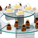 An Eastern Tabletop round tempered glass display shelf holding desserts in a bakery display.