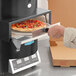 A person using a TurboChef Fire pizza oven to cook a pizza.