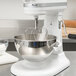 A KitchenAid mixer with a stainless steel bowl and whip on a counter.