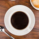 A CAC ivory china cappuccino cup on a saucer with a croissant.