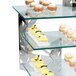 A table with glass shelves holding desserts on Eastern Tabletop stainless steel display risers.
