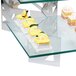 A glass display case with cakes and cupcakes on a table with Eastern Tabletop stainless steel "L" shaped corners.