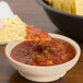 A sandstone salsa dish filled with salsa on a table with chips.