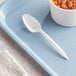 a white spoon on a blue tray